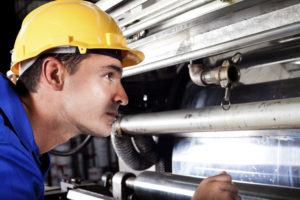 industrial machine operator checking on machine while it's running